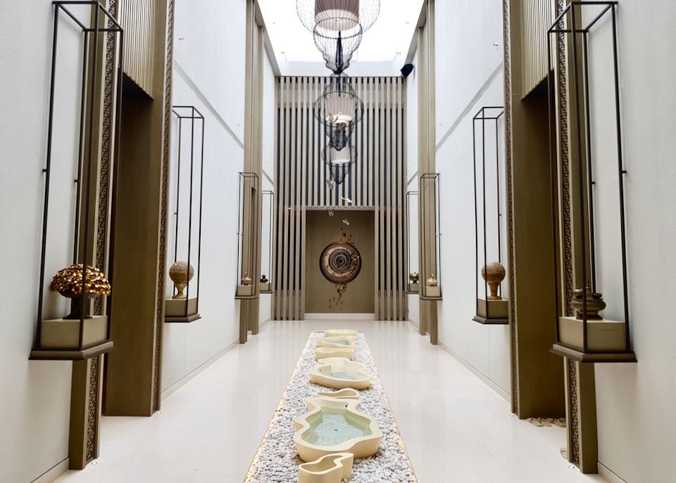 A white hallway with small fountains down the middle .