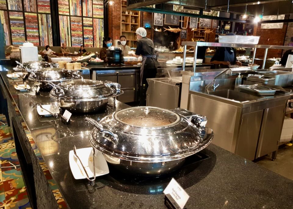 Silver covered dishes line a Buffett counter.