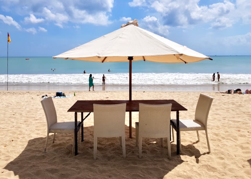 A table on the beach sits under an umbrella.
