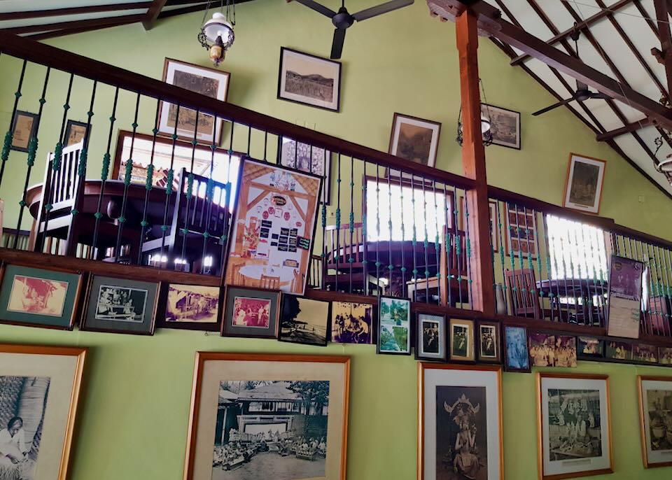 The inside of a restaurant with yellow painted walls covered with old photographs.