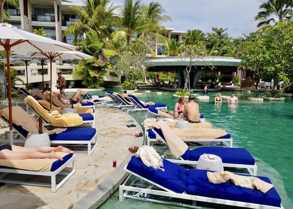 Guests sit on lounge chairs by the pool.
