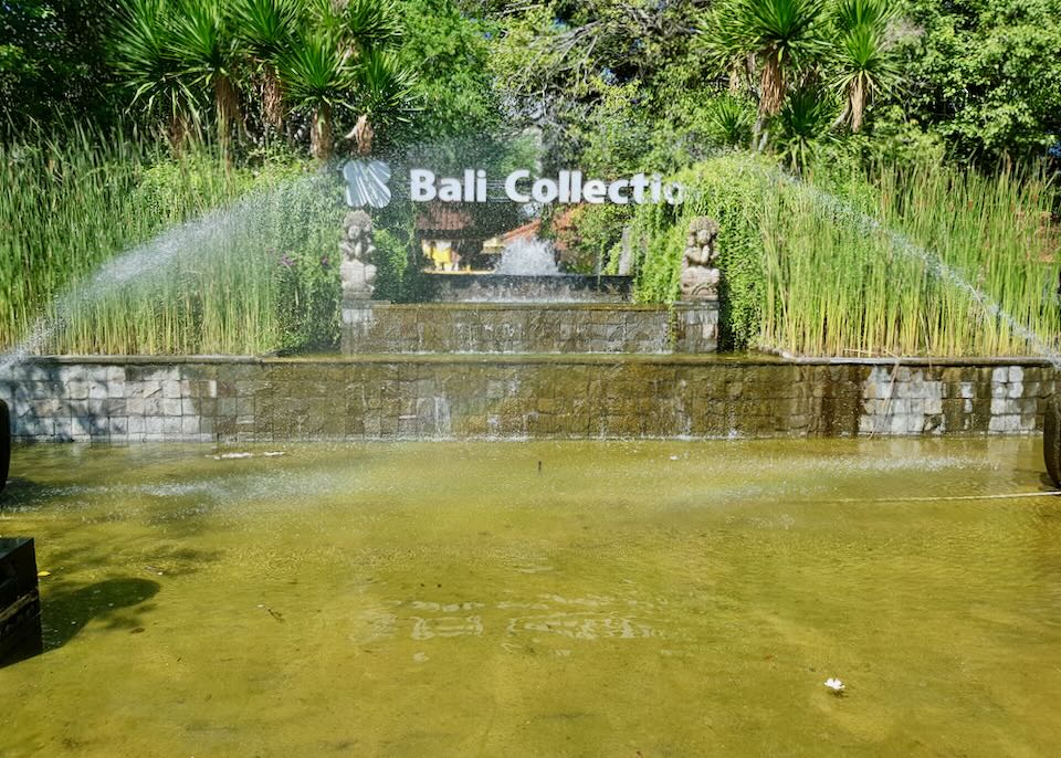 A sign for the Bali Collection sits in a fountian.