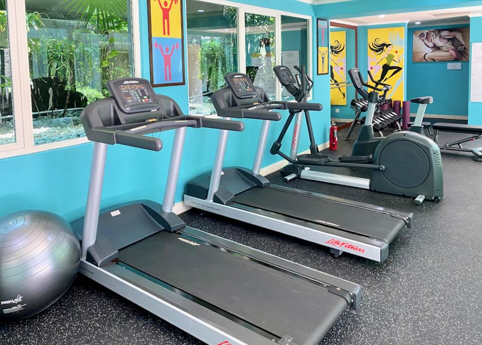 Treadmills and a stationary bike sit in a colorful gym.