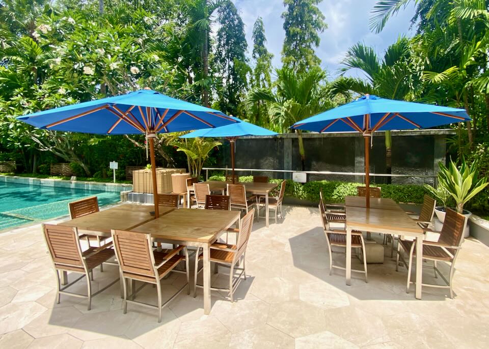 Several tables with umbrellas sit next to the outdoor pool.