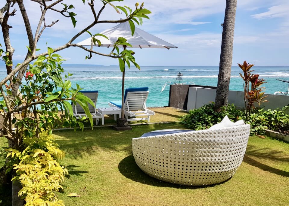 A large round chair sits by the beach.