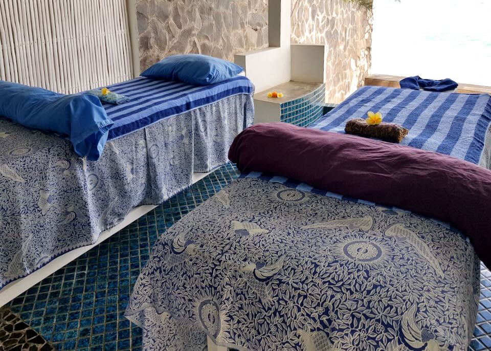 Two massage tables sit next to each other covered in blue printed clothes.