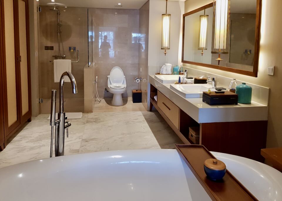 A large bathroom with a separate tub, shower, toilet, and double-sink counter.