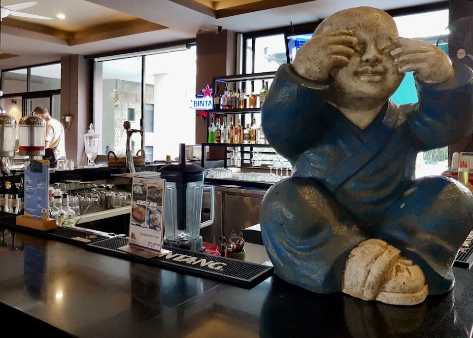 A ceramic sculpture of a buddha sits on the bar at Fat Buddha Legian.