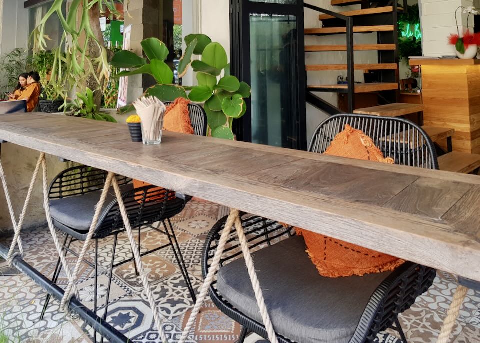 A wood counter with chairs and orange cushions at Bali Bondi Restaurant.