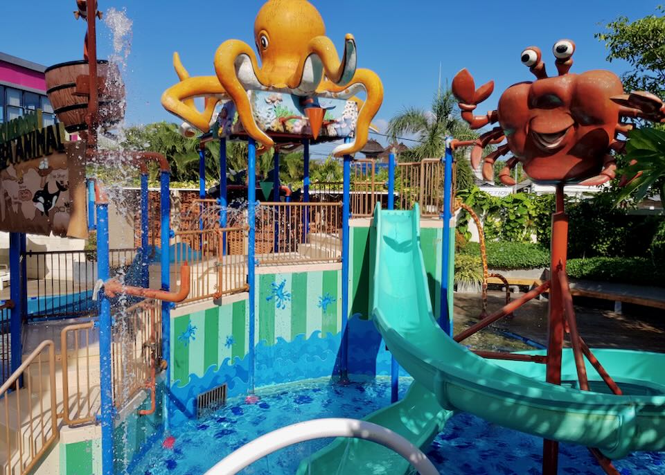 A sculpture of a red crab and yellow octopus hover over a waterslide.