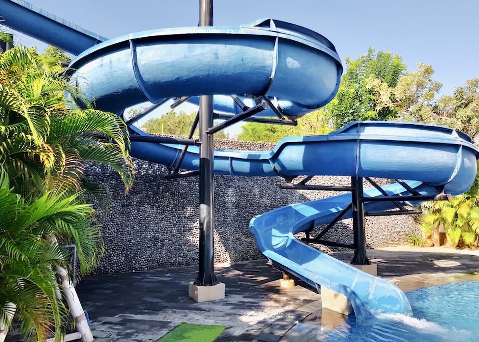 A curly blue waterslide empties into a pool.