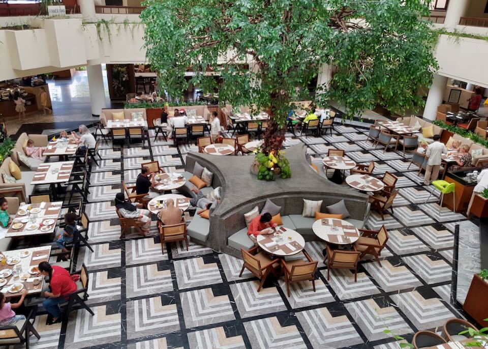 An overhead view of a restaurant in the center of a hotel with a tree in the middle.