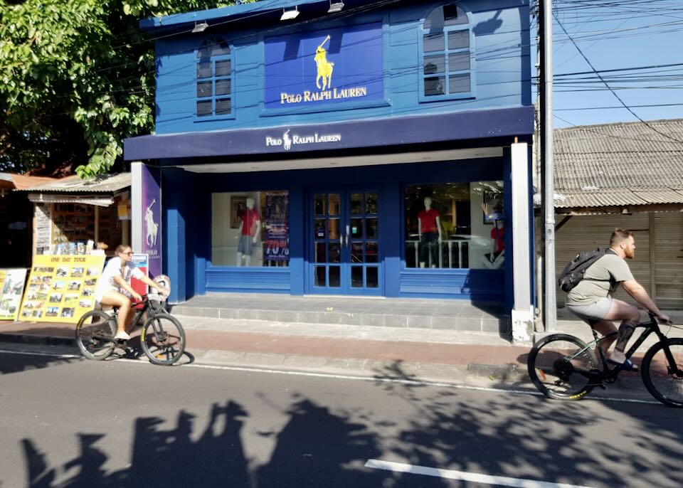 A couple rides bikes in front of a Polo Ralph Lauren store painted bright blue.