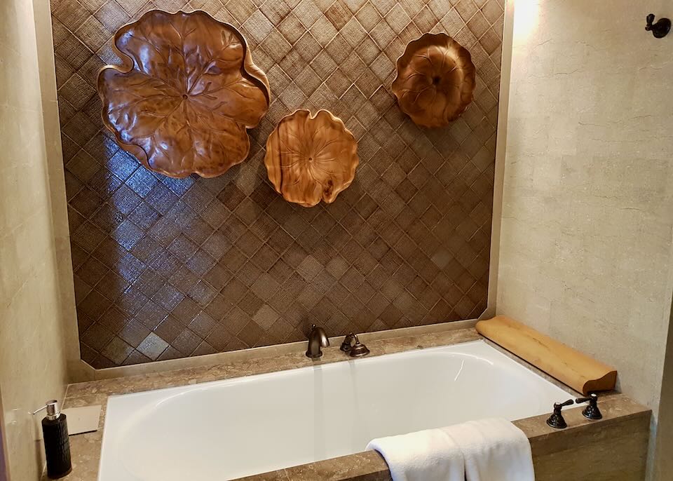 A tub in the bathroom with wood carved lily pads above it.