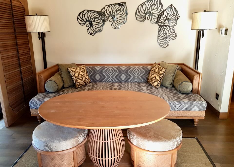 A patterned sofa with a table and two stools sits in the hotel room.