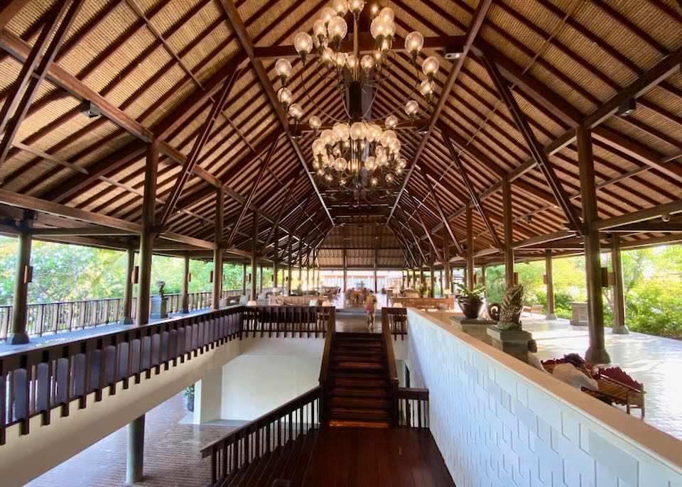 A thatched-roof with dark wood support beams support large round glass globe chandeliers.