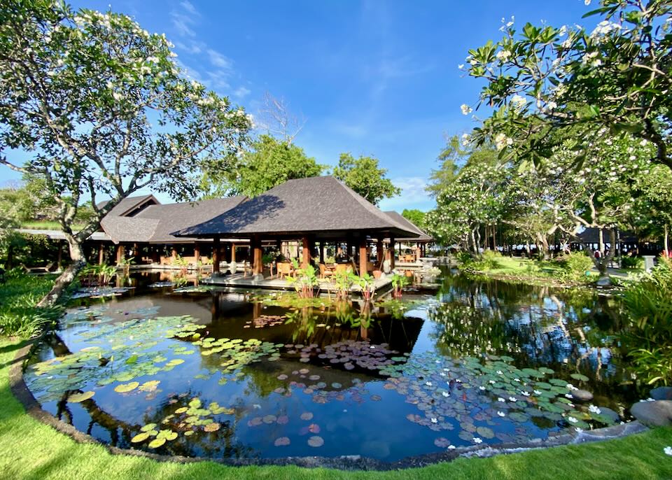 A lily pond surrounds thatched-roof canopies.