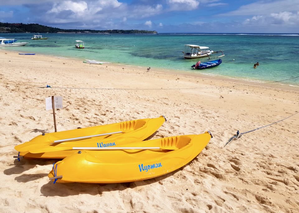 Two yellow kayaks sit on the beach.