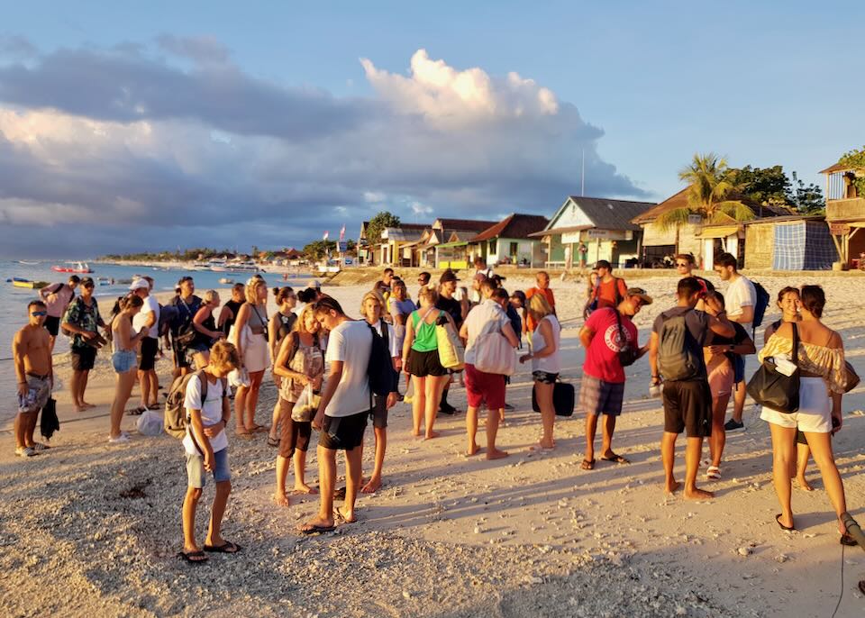 People stand on the beach waiting for a boat.
