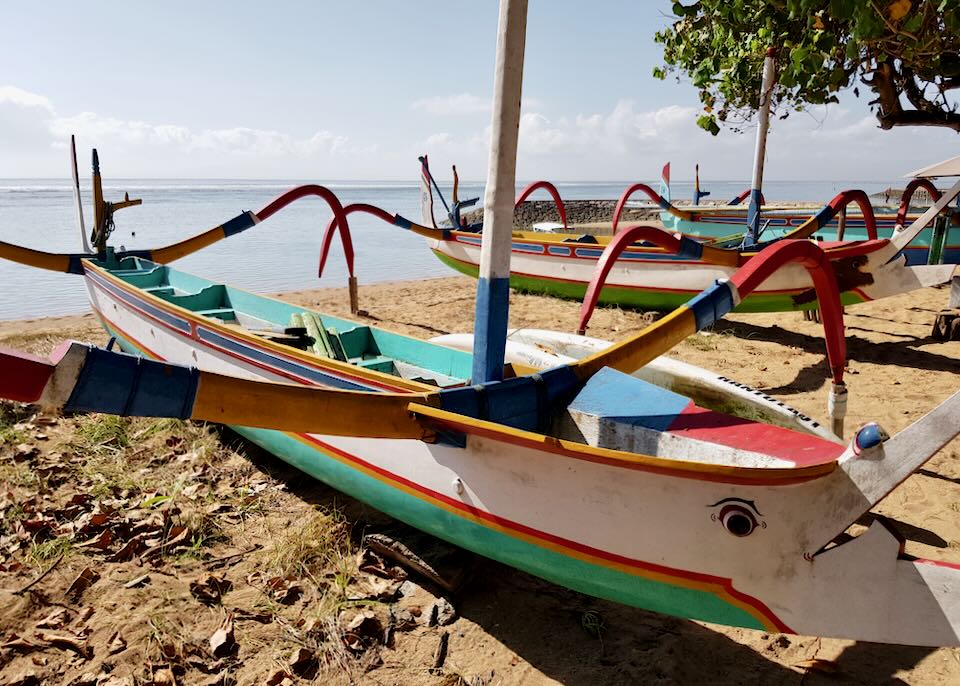 Colorful fishing boats sit on the shore.