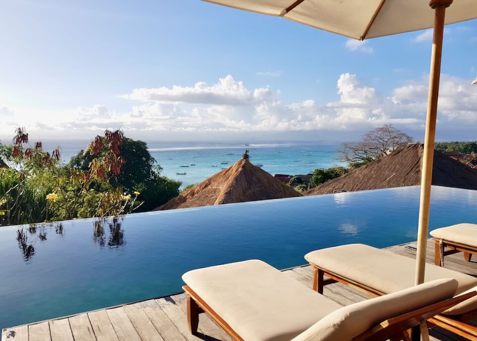 Lounge chairs by an infinity pool overlooks the ocean.