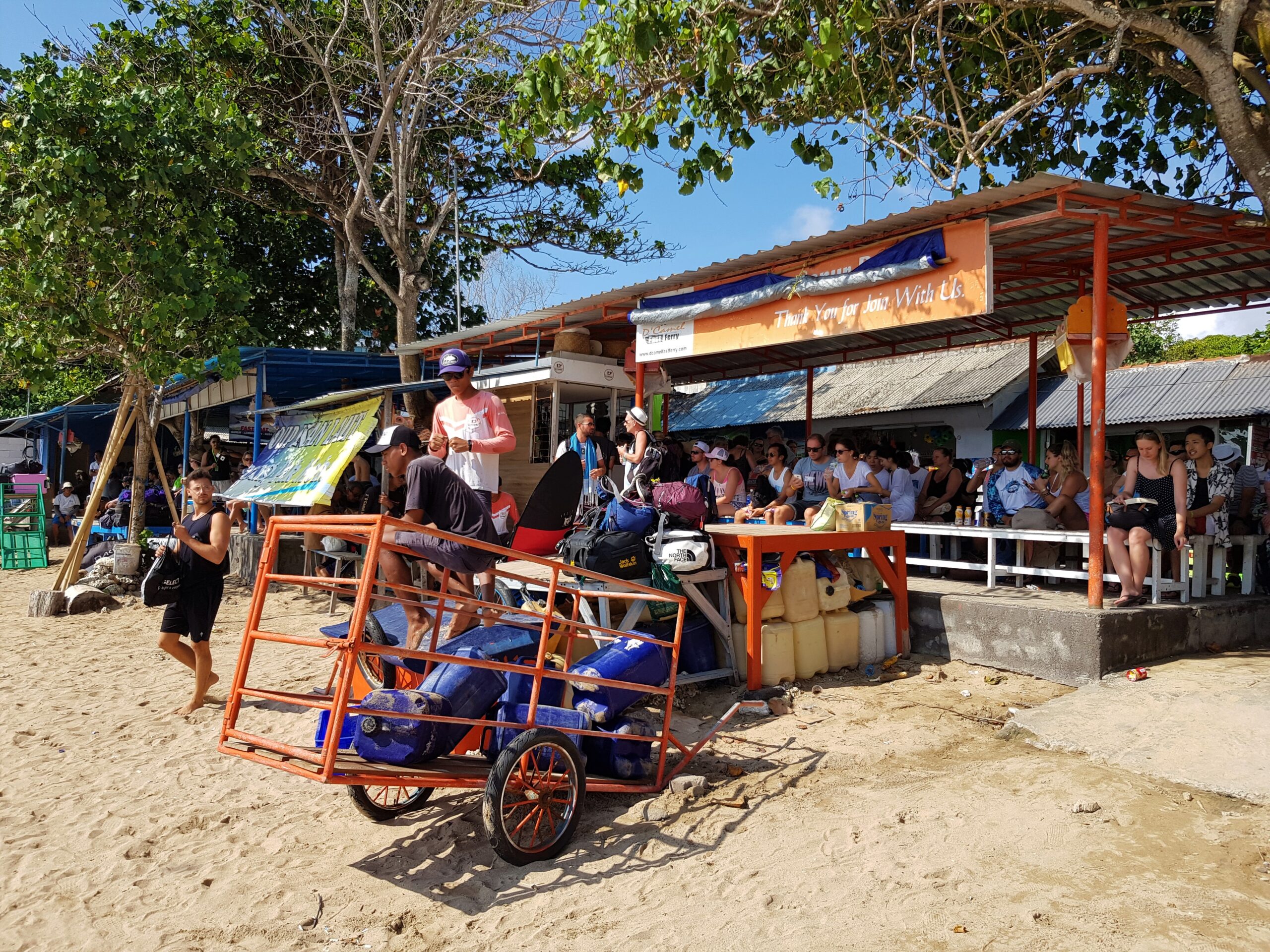 People wait under a shelter on the beach.