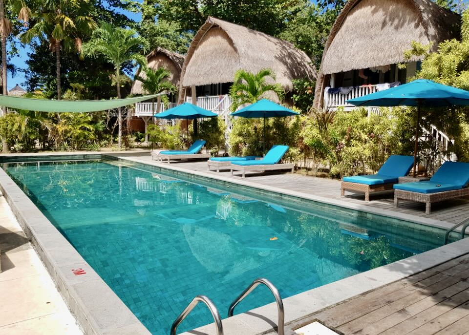 Thatched-roof cabanas sit by a pool.